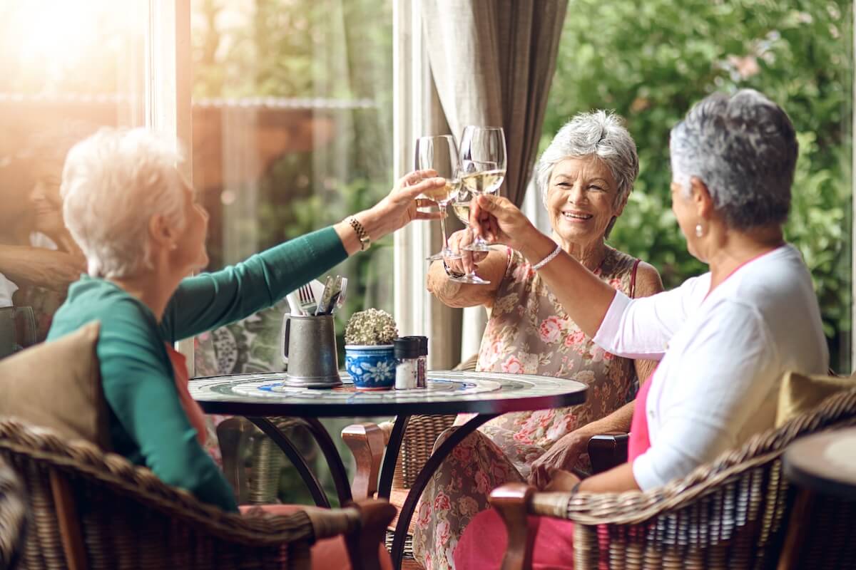 Senior woman, cheers and friends in restaurant for wine