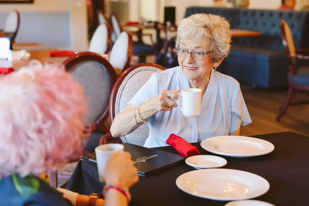 Senior women drinking coffee and talking in dining room at Addington Place of East Lake