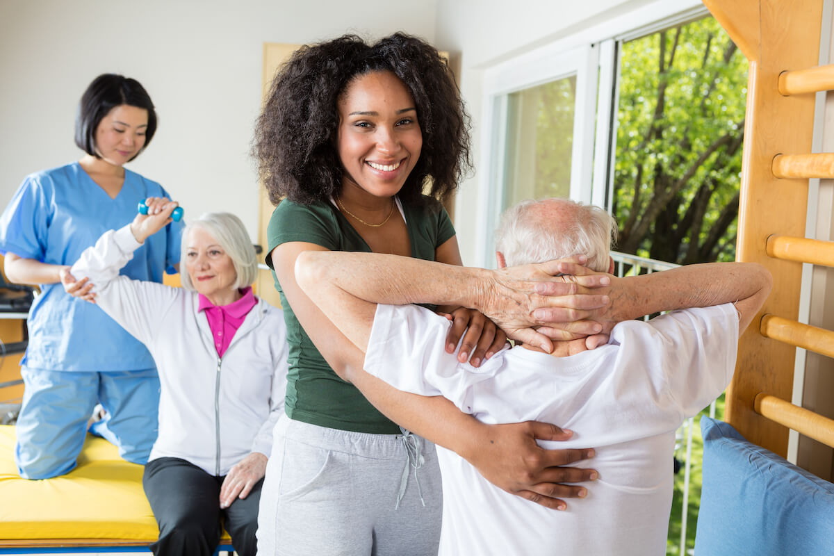 Caregivers helping seniors stretch in a senior living community