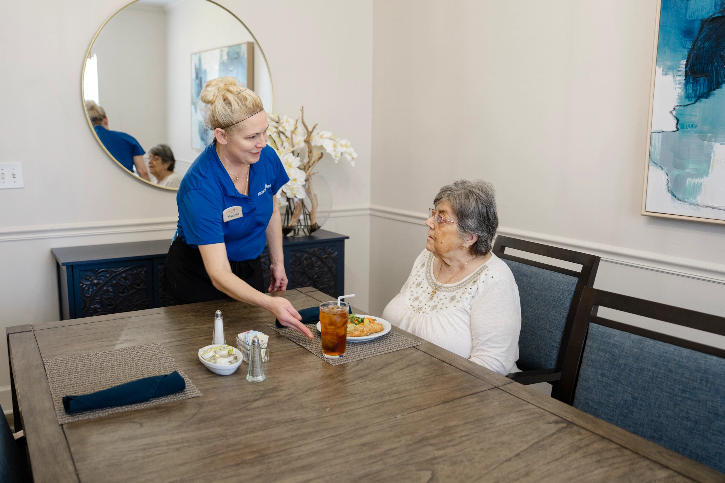 Server interacting with seated resident at dining booth